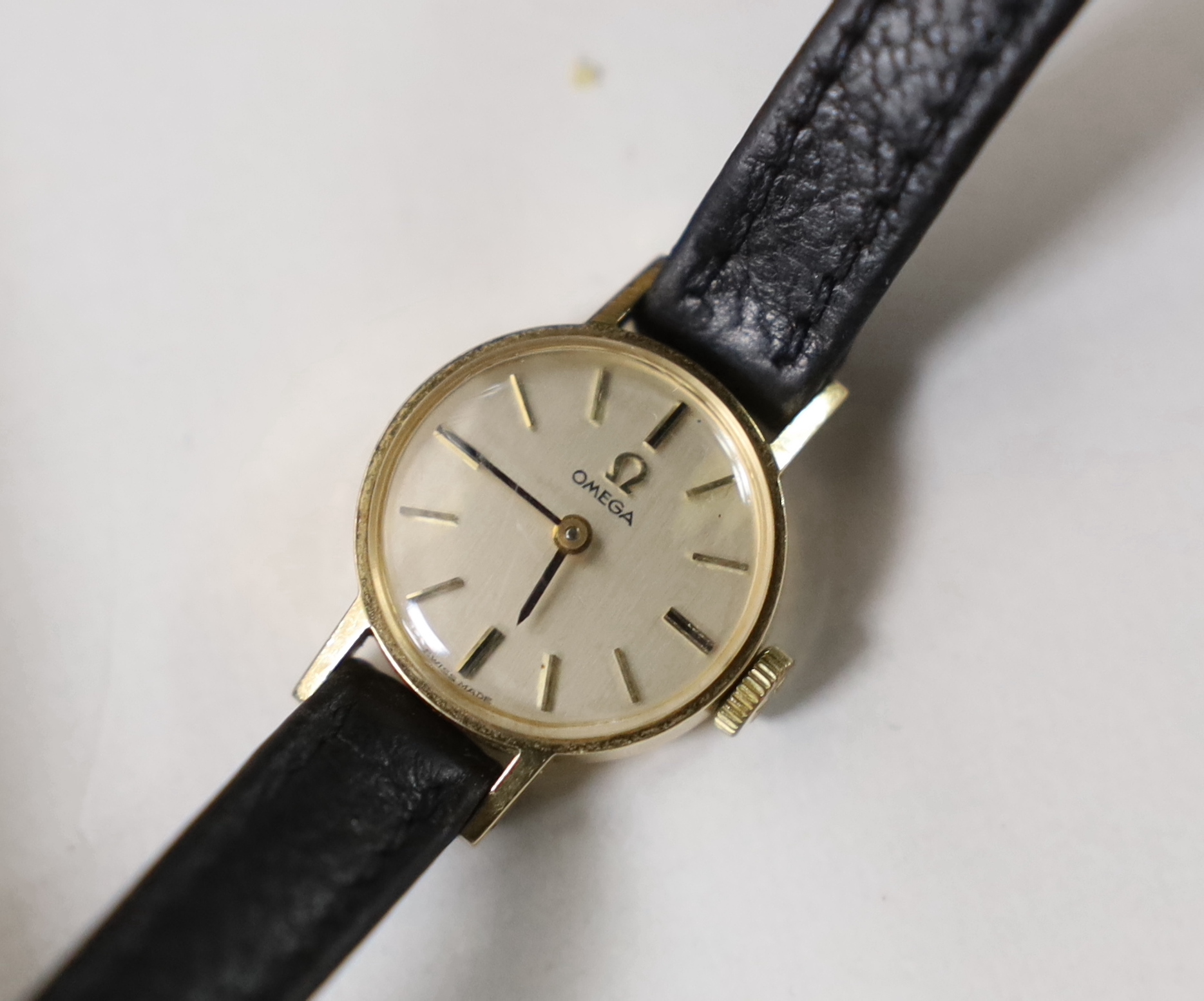 A lady's 1960's 9ct gold Omega manual wind wrist watch, on a leather strap with Omega buckle, the case back with inscription, with paperwork, no box.